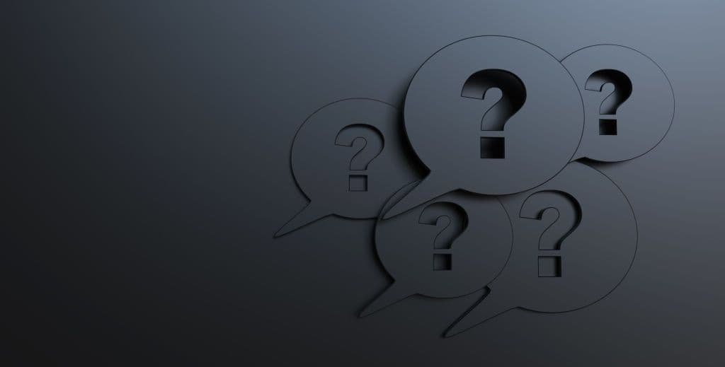 Five dark 3D speech bubbles on a grey wall, each embossed with a question mark.